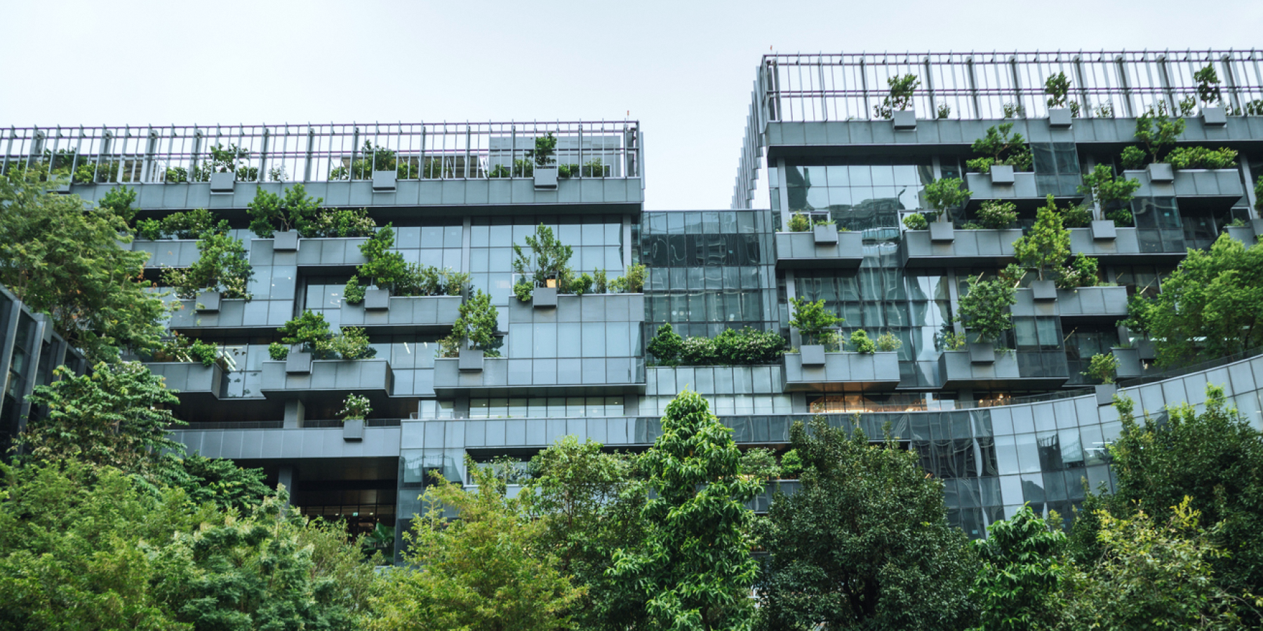 A building with integrated planters and greenery on multiple levels, surrounded by trees.